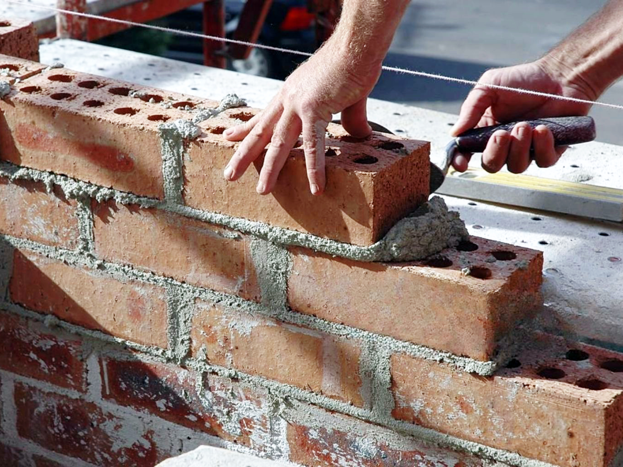 Maurer beim Mauern mit Richtschnur